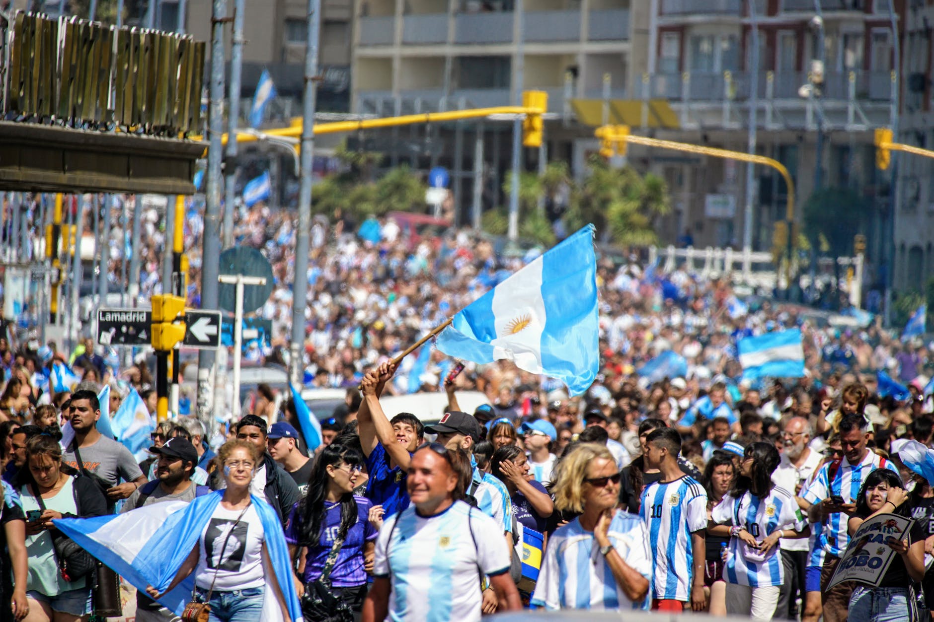 a crowd of people walking down a street with argentina flags