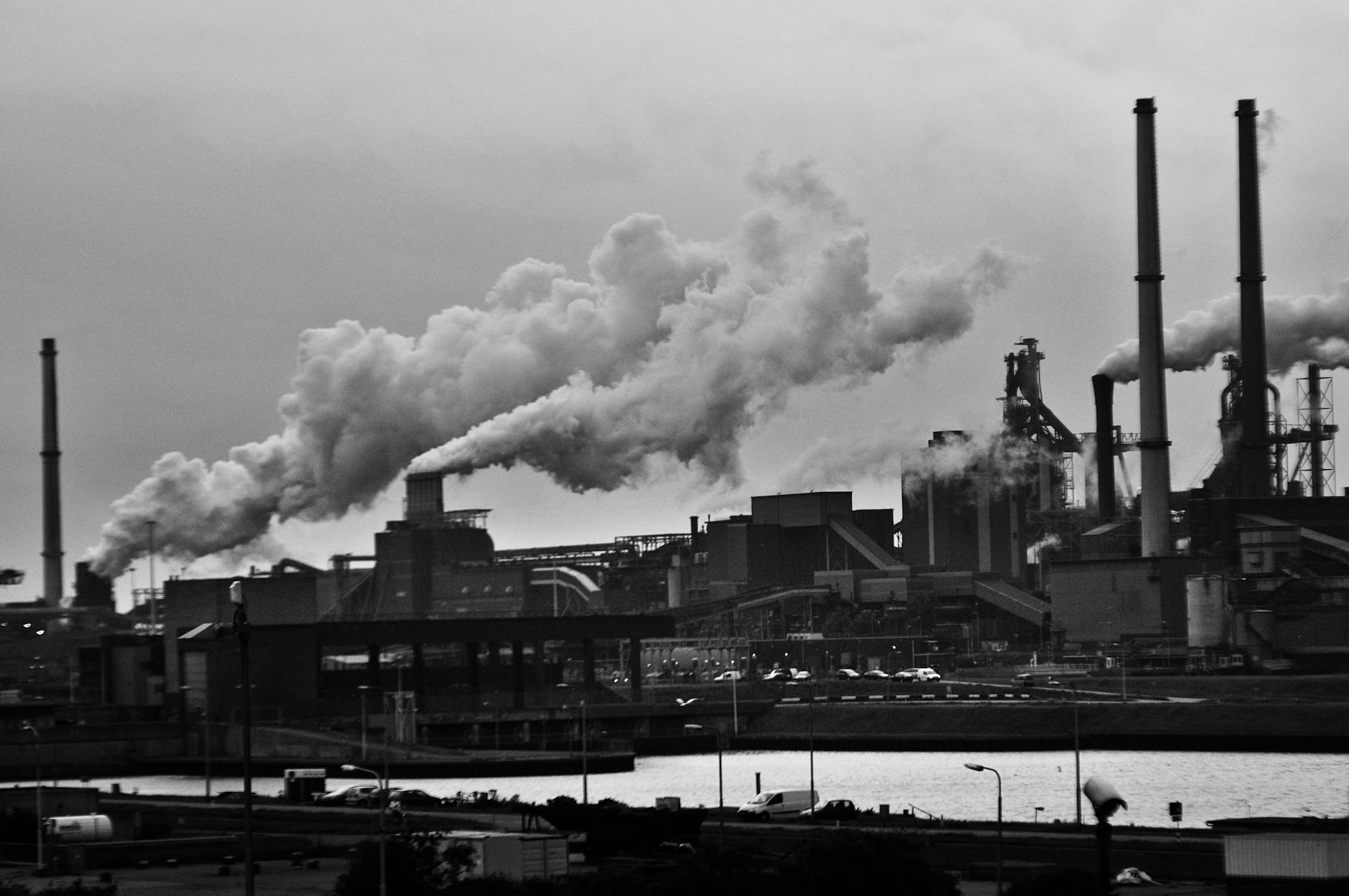 grayscale photography of locomotive train beside factory